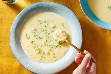 Corn chowder served inside a soup plate, sprinkled with sliced scallions