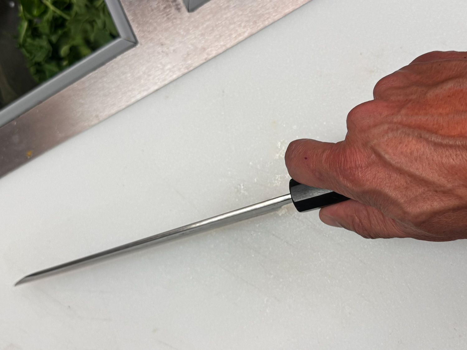 A hand holding a knife over a cutting board