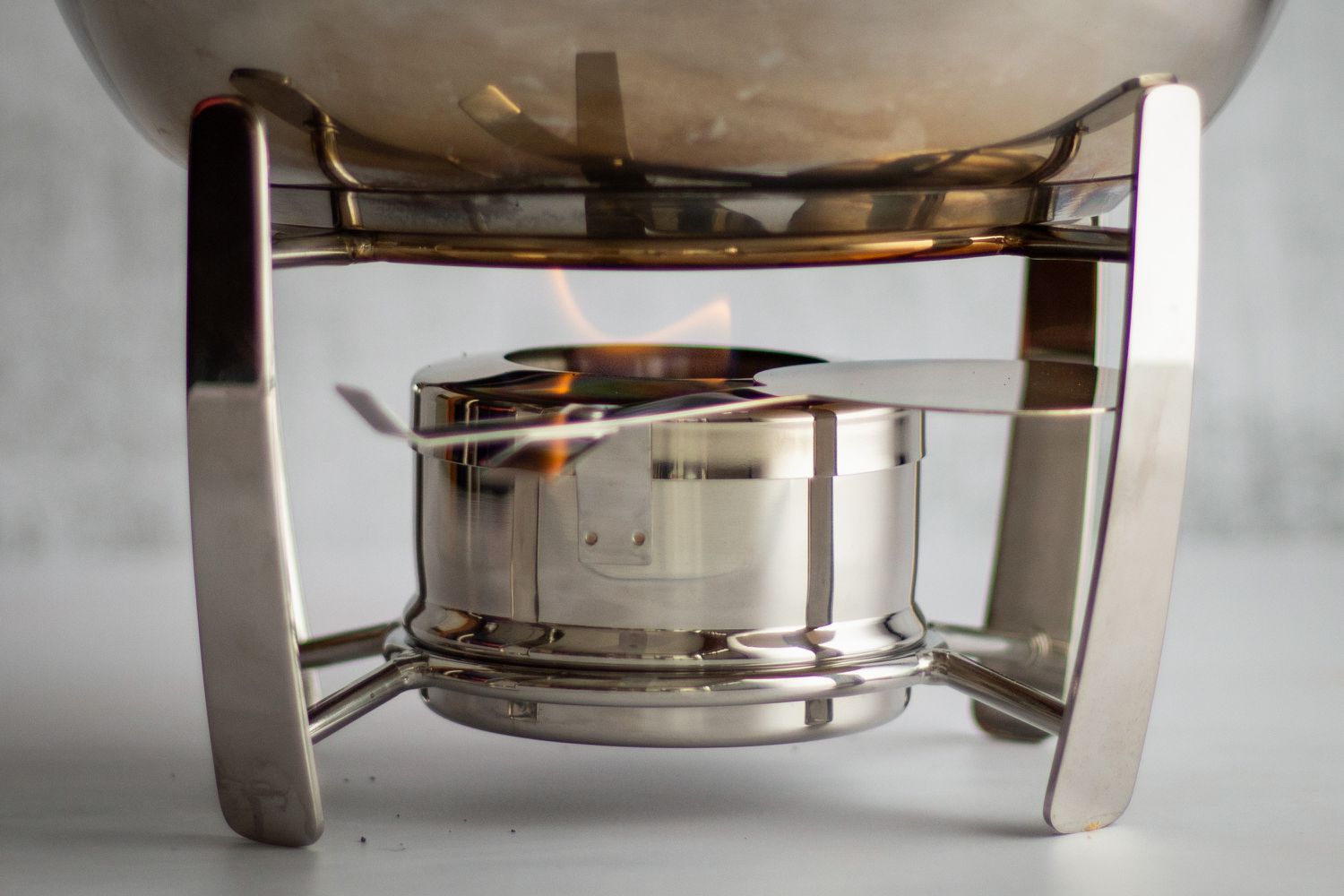 A stainless steel fondue pot with a flame underneath it. 