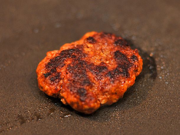 Closeup of a test patty browning in a nonstick skillet.