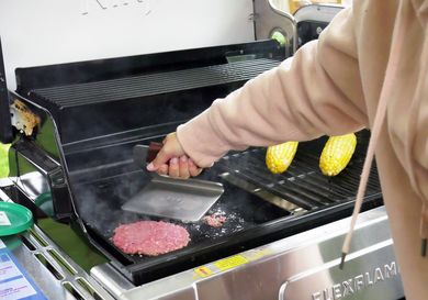 a person using a grill press to smash burgers on a griddle in a grill