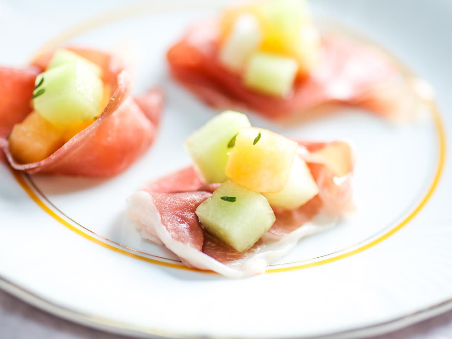 Closeup of the melon salad loosely wrapped into bit-sized parcels with slices of prosciutto, ready to serve.