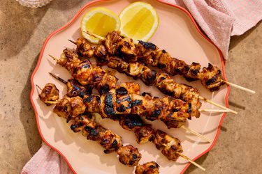 Honey harissa glazed chicken skewers on a platter with lemon slices