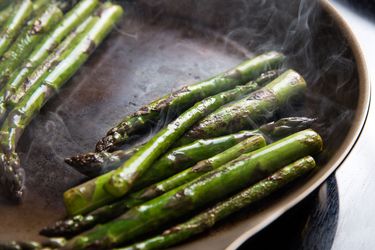 Asparagus sautéing in a pan.