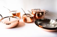 A set of pots and pans with lids arranged on a white surface