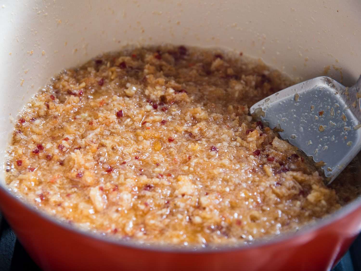 Ingredients for XO sauce (dried seafood, ham, ginger, garlic, chiles, and shallots) cooking down in a Dutch oven.