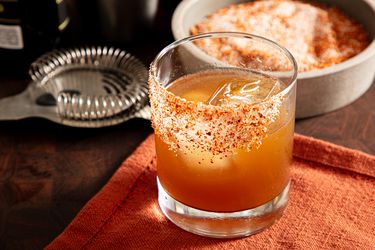A prepared margarita cocktail with a spicy rim garnish placed on an orange napkin