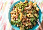 A bowl of fingerling potato salad with chorizo, onion, and arugula. 