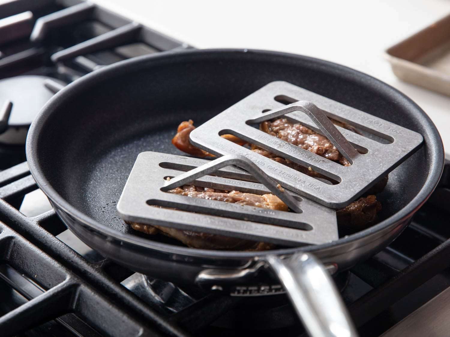 Crisping duck legs under weights in a nonstick pan.