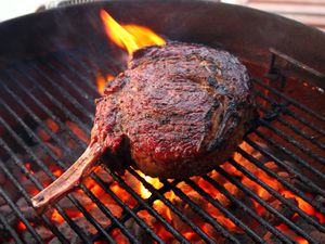 A bone-in ribeye steak on a hot grill.