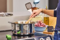 A person stirs food in the All-Clad Copper Core 10-Piece Cookware Set pot