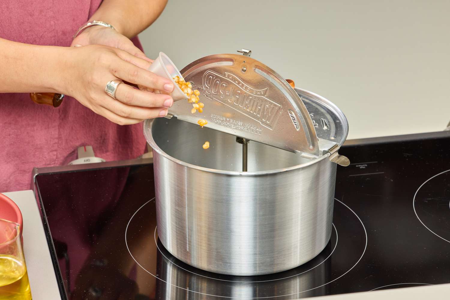 A person pours popcorn kernels into the Wabash Valley Farms Original Whirley-Pop Popcorn Popper Stainless Steel