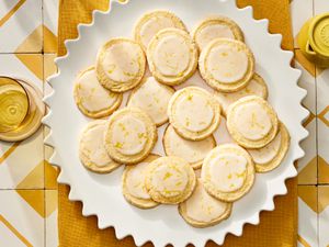Plate of lemon sugar cookies on a yellow textile on top of yellow and white tiles. 