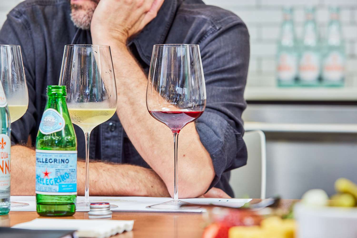 Three wine glasses on a table with a man in the background.