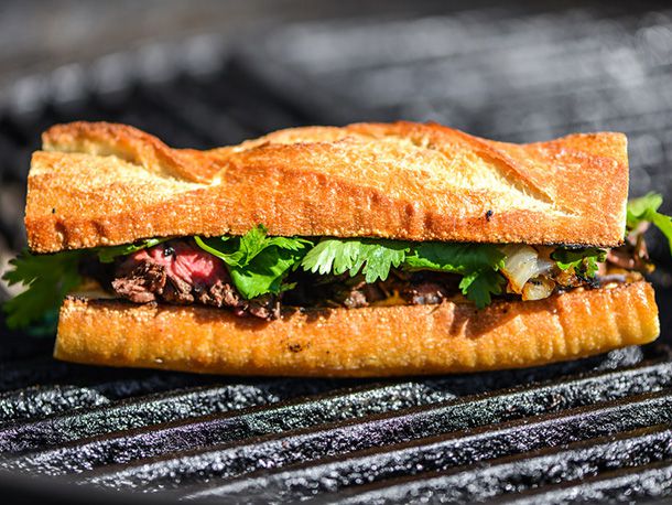 Assembled baguette steak sandwich on grill surface
