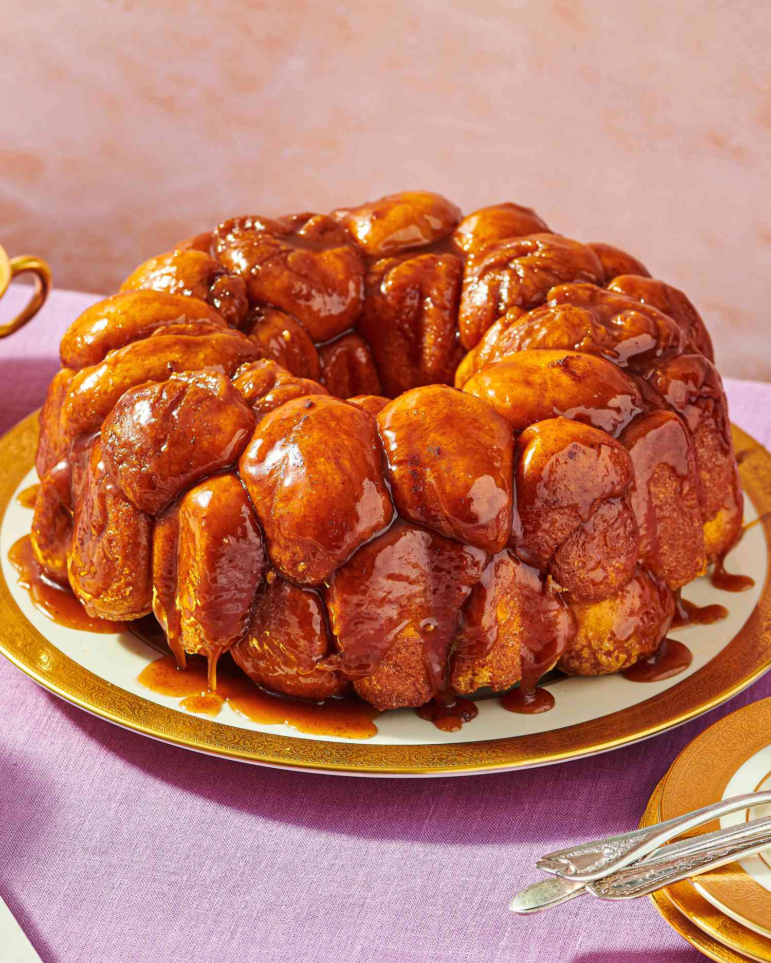 A plate of monkey bread on a table with utensils nearby