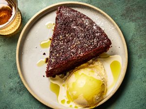 A slice of chocolate olive oil cake served with a scoop of ice cream on a plate