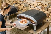 A person cooks a pizza in the Ooni Koda 2 Pro Gas-Powered Pizza Oven