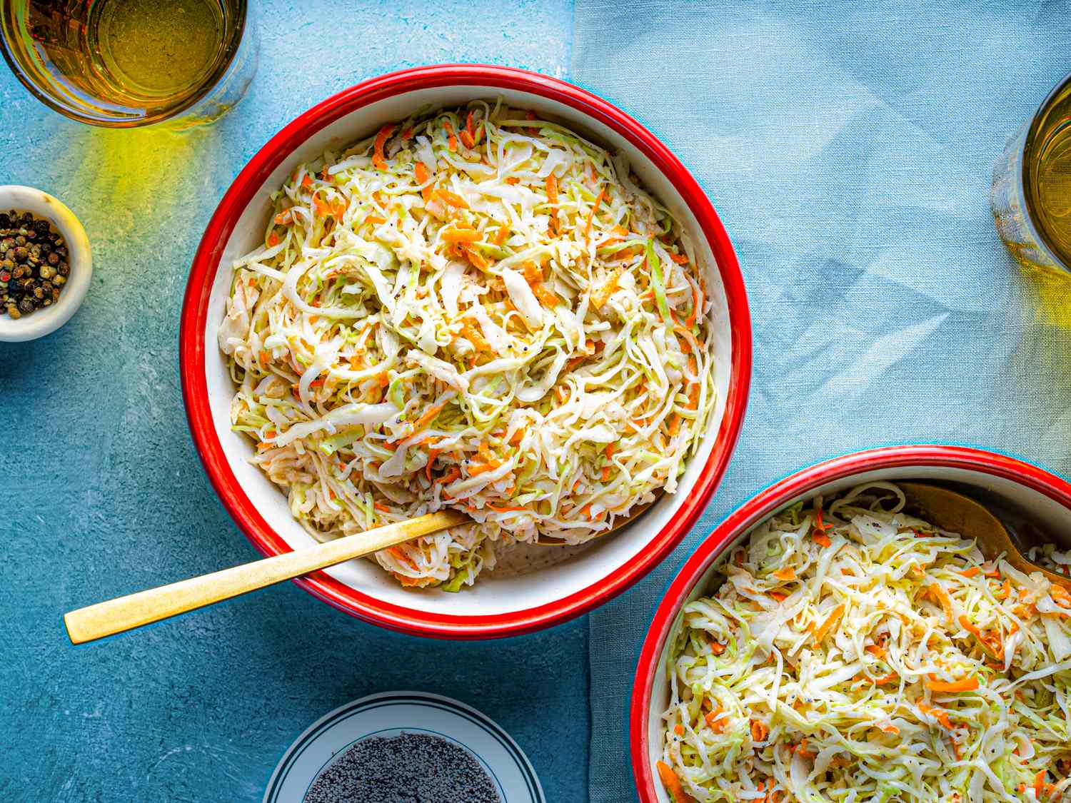 Two bowls of coleslaw with a wooden spoon on one