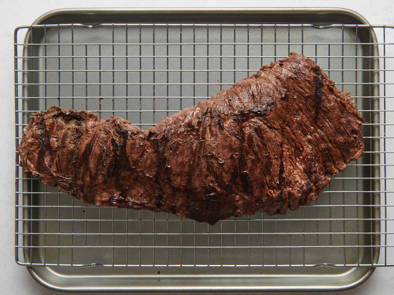 Well-browned steak transferred to a wire rack set in a rimmed baking sheet