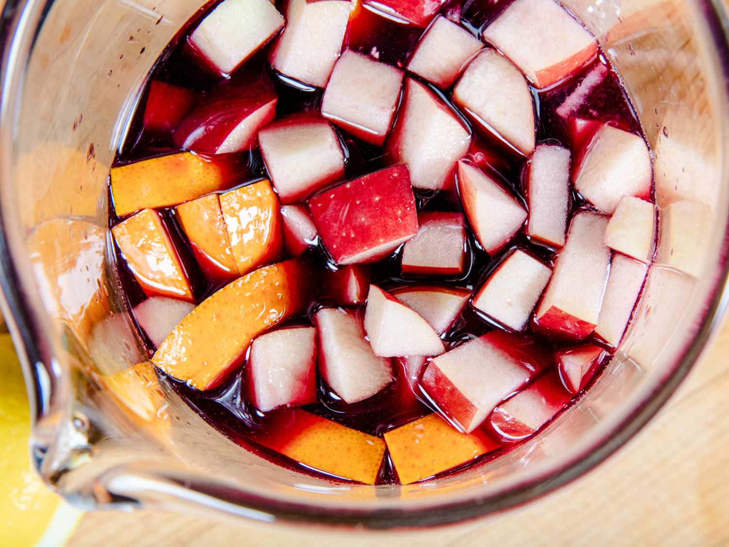 Diced apples and oranges in a wine-based liquid.