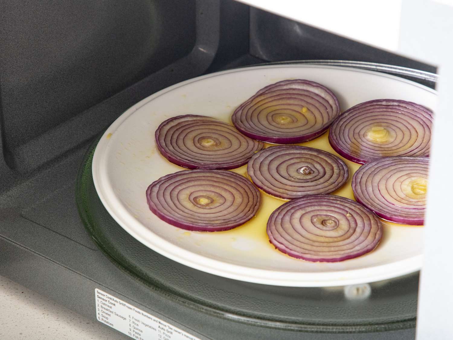 Sliced onions being heated on a microwave-safe plate
