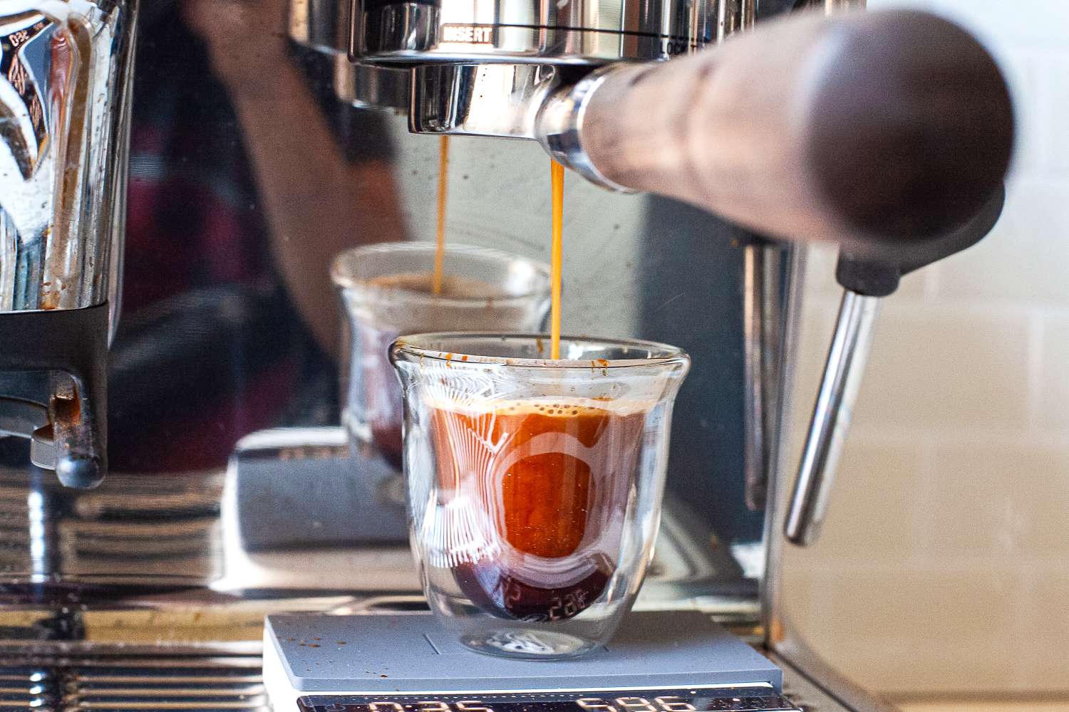 Espresso machine pouring coffee into a glass cup on a scale