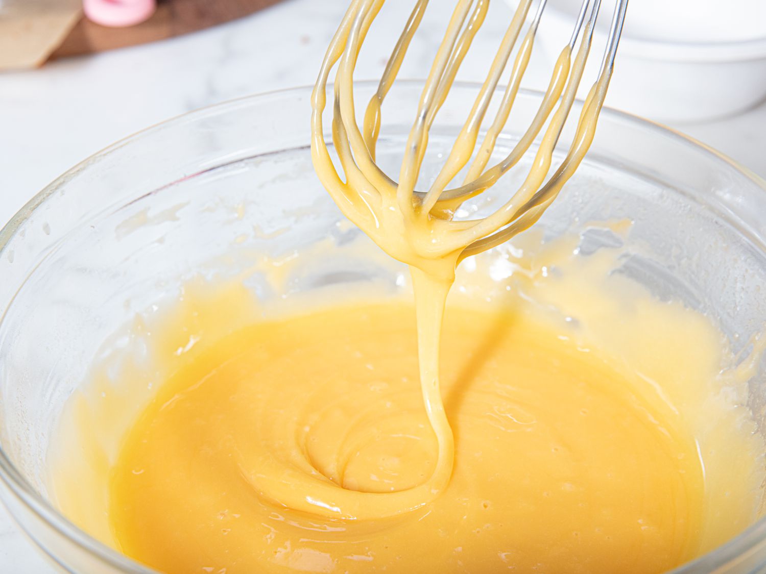 Cheese sauce being whisked in glass bowl.