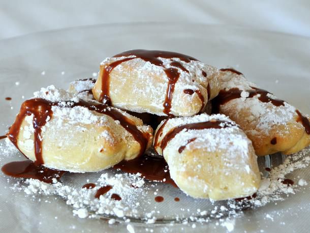 Beignets sprinkled with confectioners' sugar and drizzled with chocolate sauce.