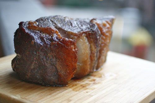 Side view of cooked prime rib roast on a wooden cutting board.