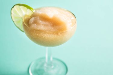 Frozen daiquiri in a coupe glass garnished with a lime wheel.