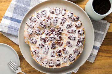 Yeasted coffee cake on wooden table with blue and white plaid napkin, cup of coffee and small plate