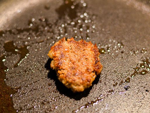 Frying a small piece of lamb sausage in a cast iron skillet to test the seasoning.
