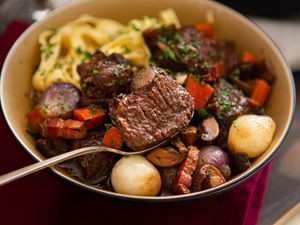 A bowl of beef stew with vegetables and garnished herbs