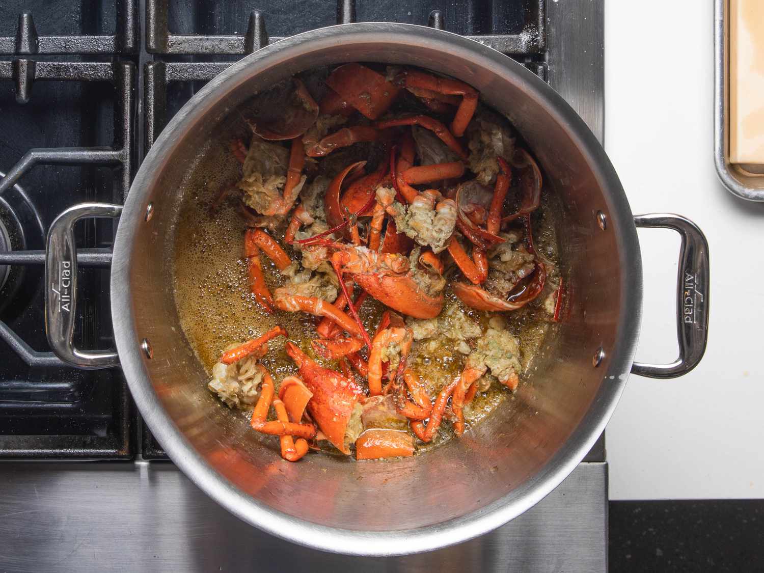 The lobster bodies frying gently in oil in the pot.