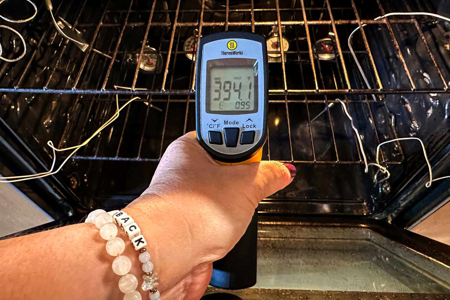 A person uses an infrared thermometer to test how hot an oven is.