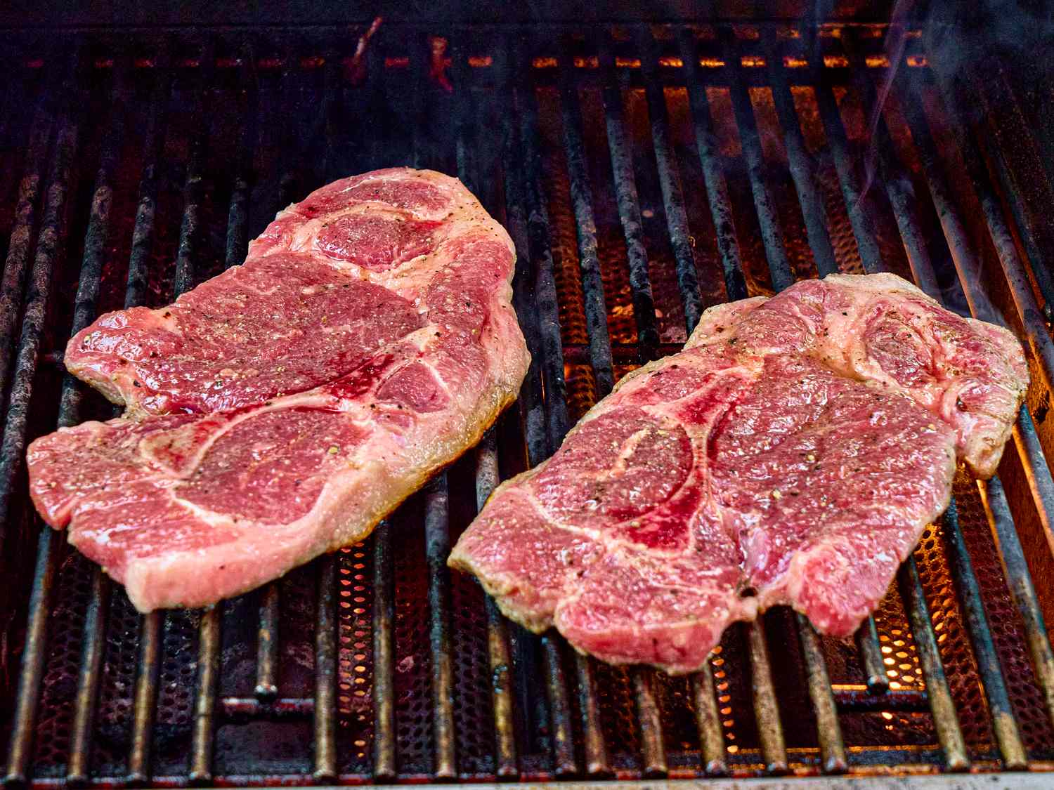 Two pork steaks on a grill