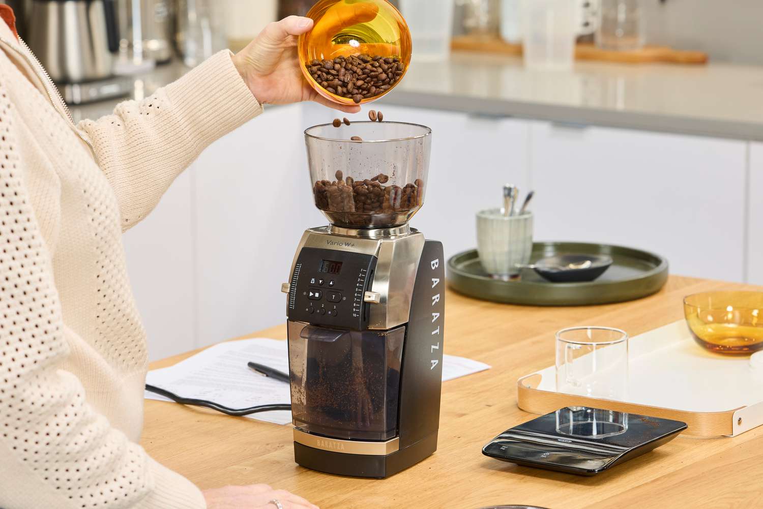 A person pours coffee beans into the Baratza Vario W+ Flat Steel Espresso Grinder