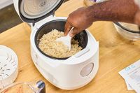 A person scoops rice from the Cuckoo 6-Cup Micom Rice Cooker