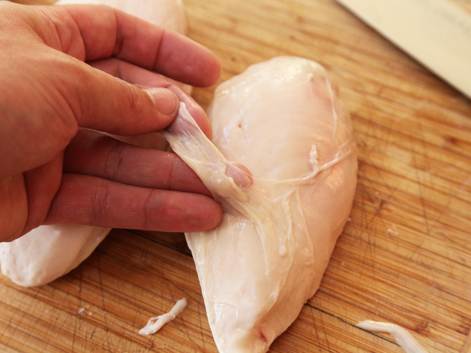 Peeling membrane off a chicken breast cooked sous vide.