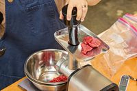 A person places cuts of meat into the Cuisinart Electric Meat Grinder