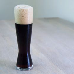 A tall pint glass of very dark doppelbock beer.
