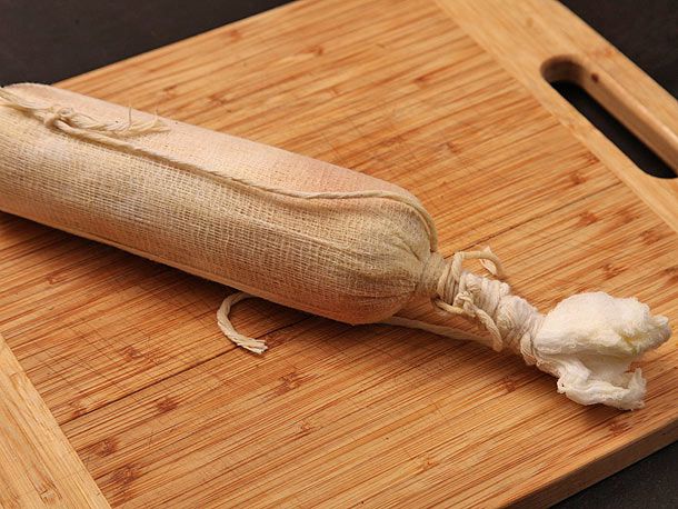 The briefly poached foie gras torchon, laying on a cutting board.