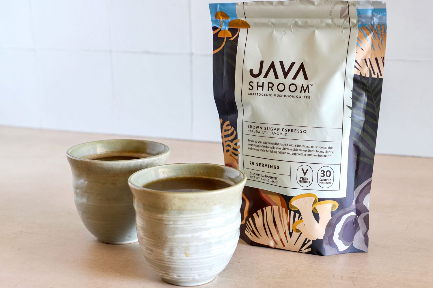 Two cups of coffee next to a bag of Java Shroom adaptogenic mushroom coffee