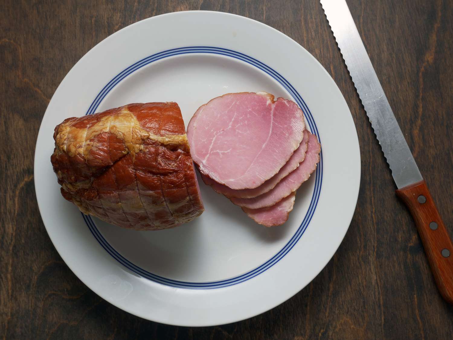 the olympia provisions ham on a plate with four slices to the side and a bread knife next to it