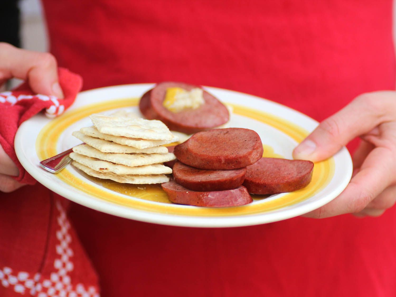 Someone holding a platter with Midwestern bologna and crackers.