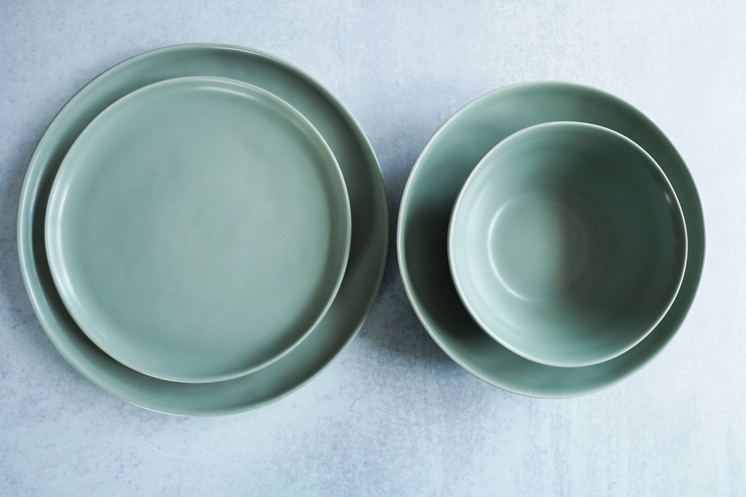Two green bowls and plates on a grey surface
