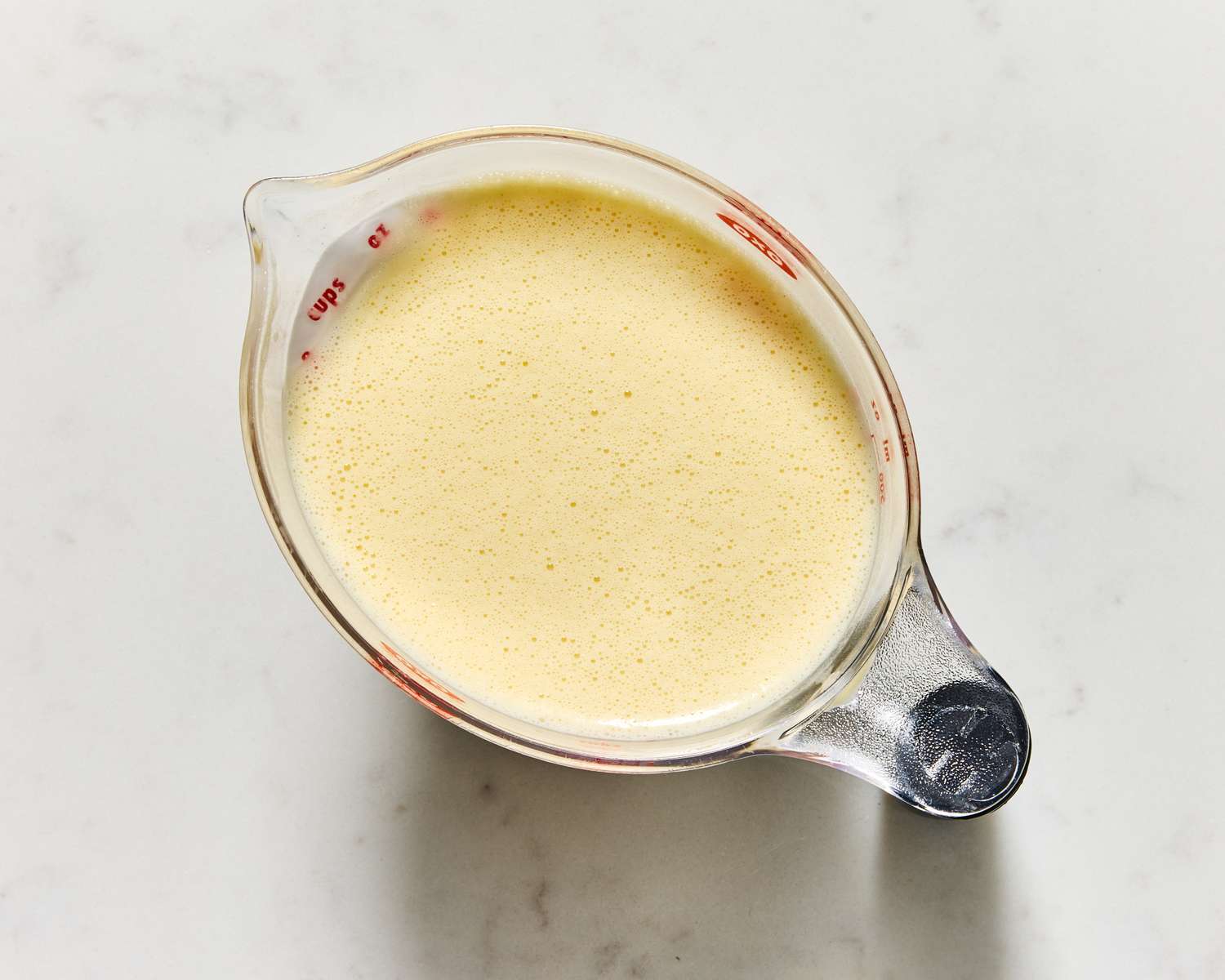 A glass measuring jug containing pancake batter