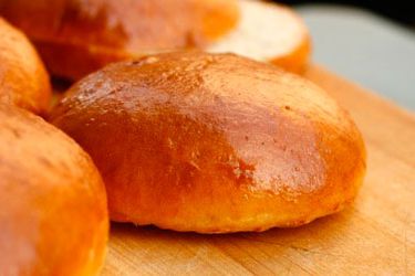 Freshly made hamburger buns on a cutting board. 