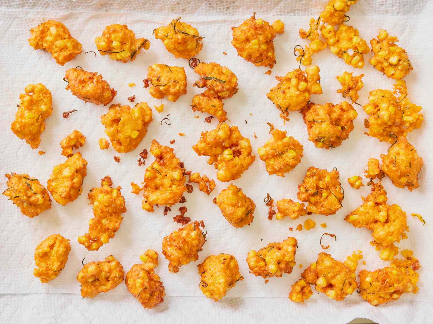 Fritters cooling on a paper towel lined platter 